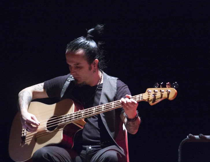 a young man sitting on the floor playing guitar