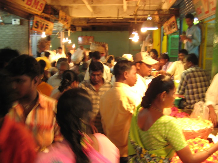 a crowd of people standing inside of a market