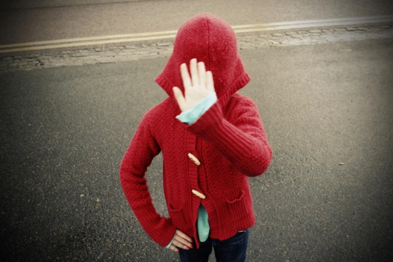 a young man wearing a red hooded sweater, with his hand up and his arms raised