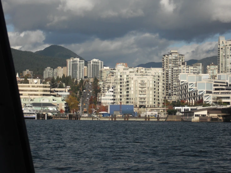 the city across the water from a dock is under heavy clouds