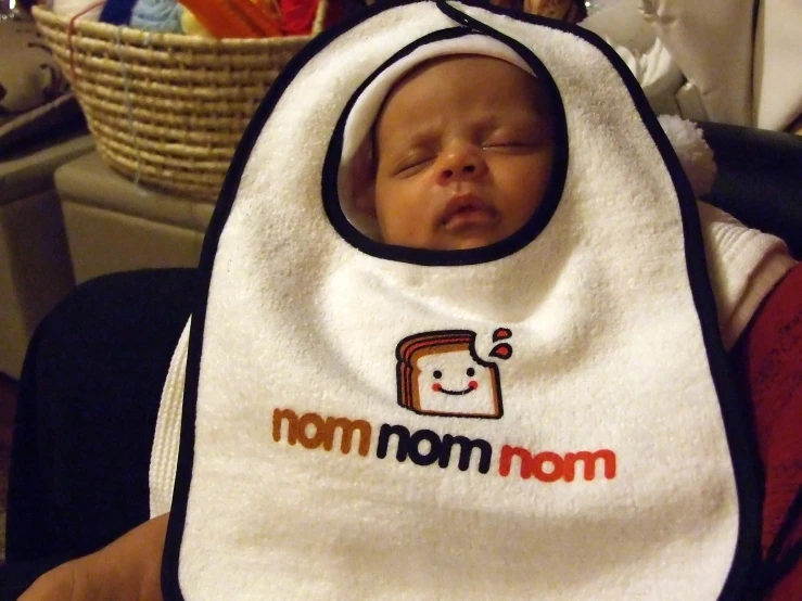 a newborn baby wearing a bib that reads mom on the front