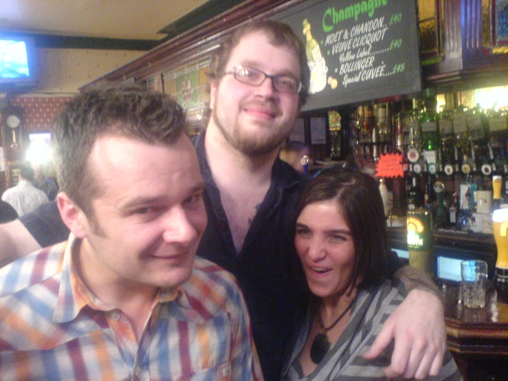 three smiling men in a bar with bottles of alcohol