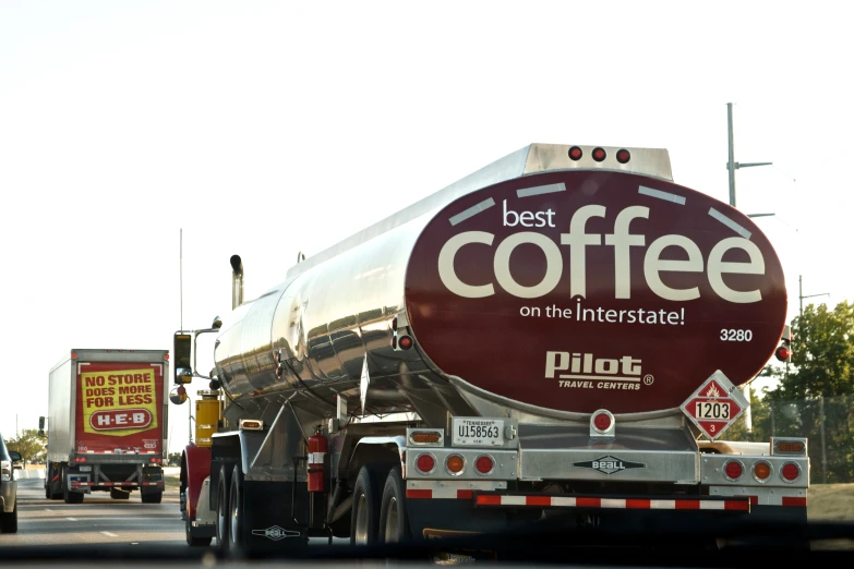 two large tankers carrying coffee parked in traffic on a city street