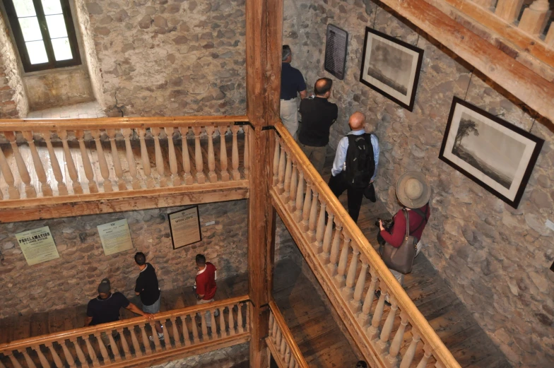 three men looking down at paintings on display