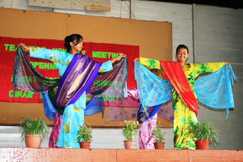 two women with large ties are holding colorful clothing