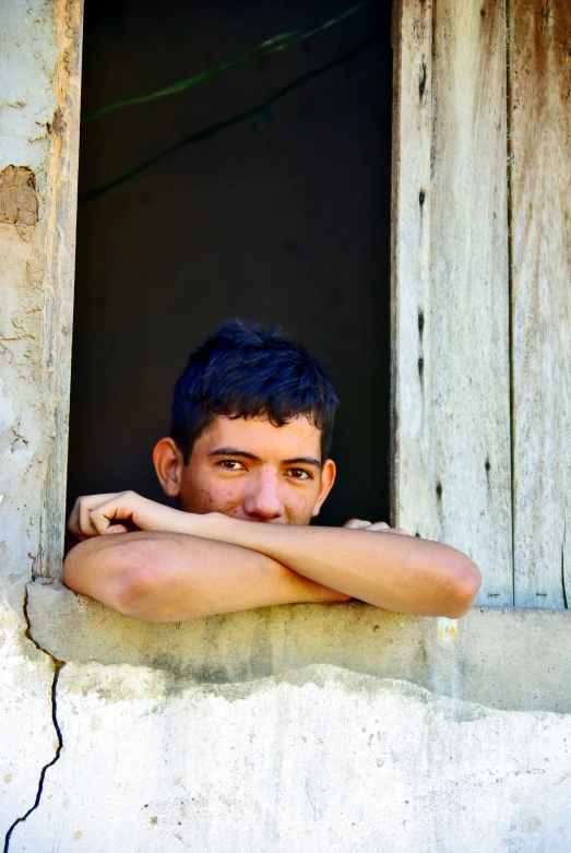 a young man is standing in an open window