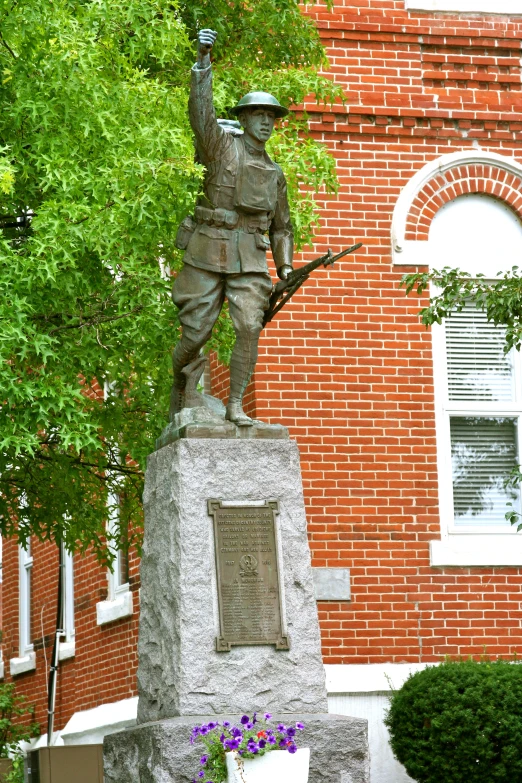 a statue in front of a brick building holding an american flag
