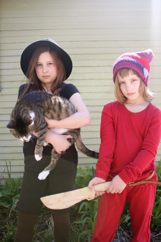 the two little girls are holding the cat