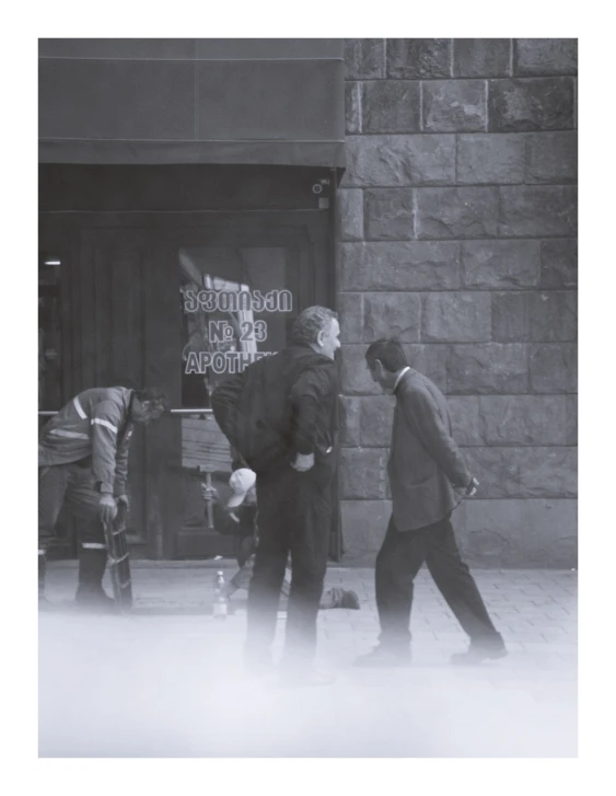 two men walking next to each other down the sidewalk