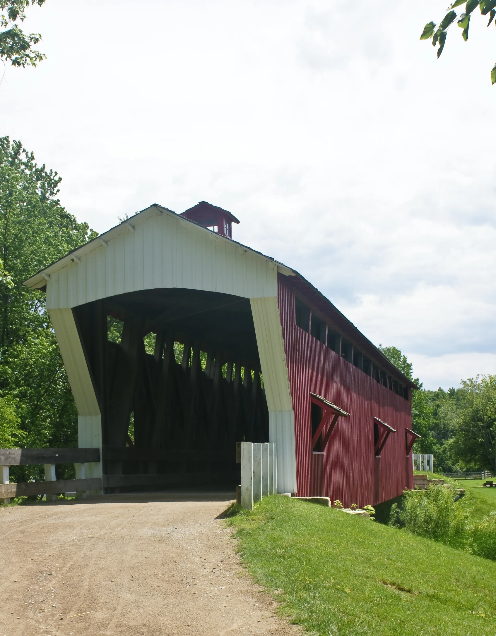 red and white covered barn with grass in the foreground