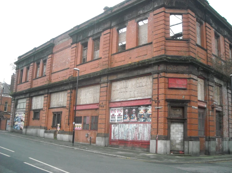 the front side of an old brick building with boarded up windows