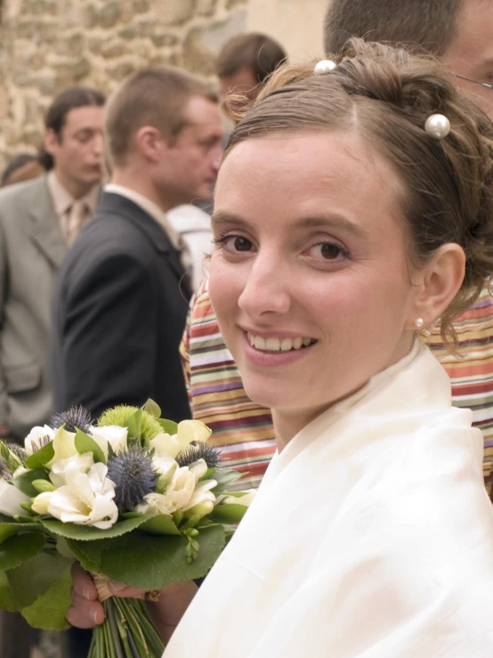 a woman smiles at the camera, in front of a group of people