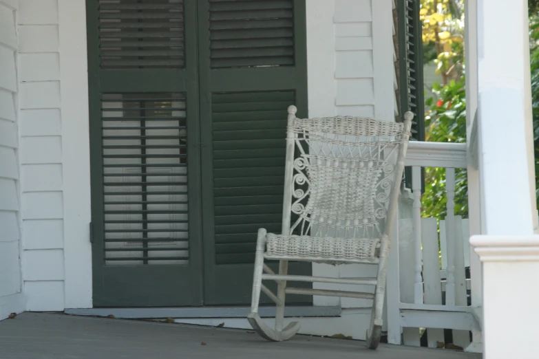 a white rocking chair on front porch of a house