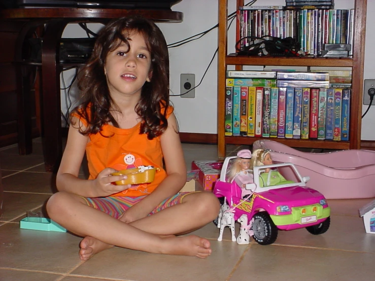 a girl in a orange shirt and some toy cars