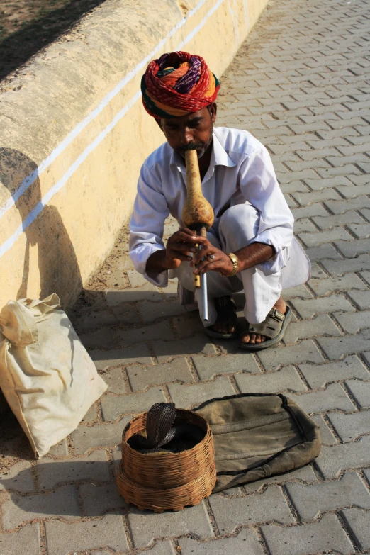 a man sits on the sidewalk, with his cane and bag