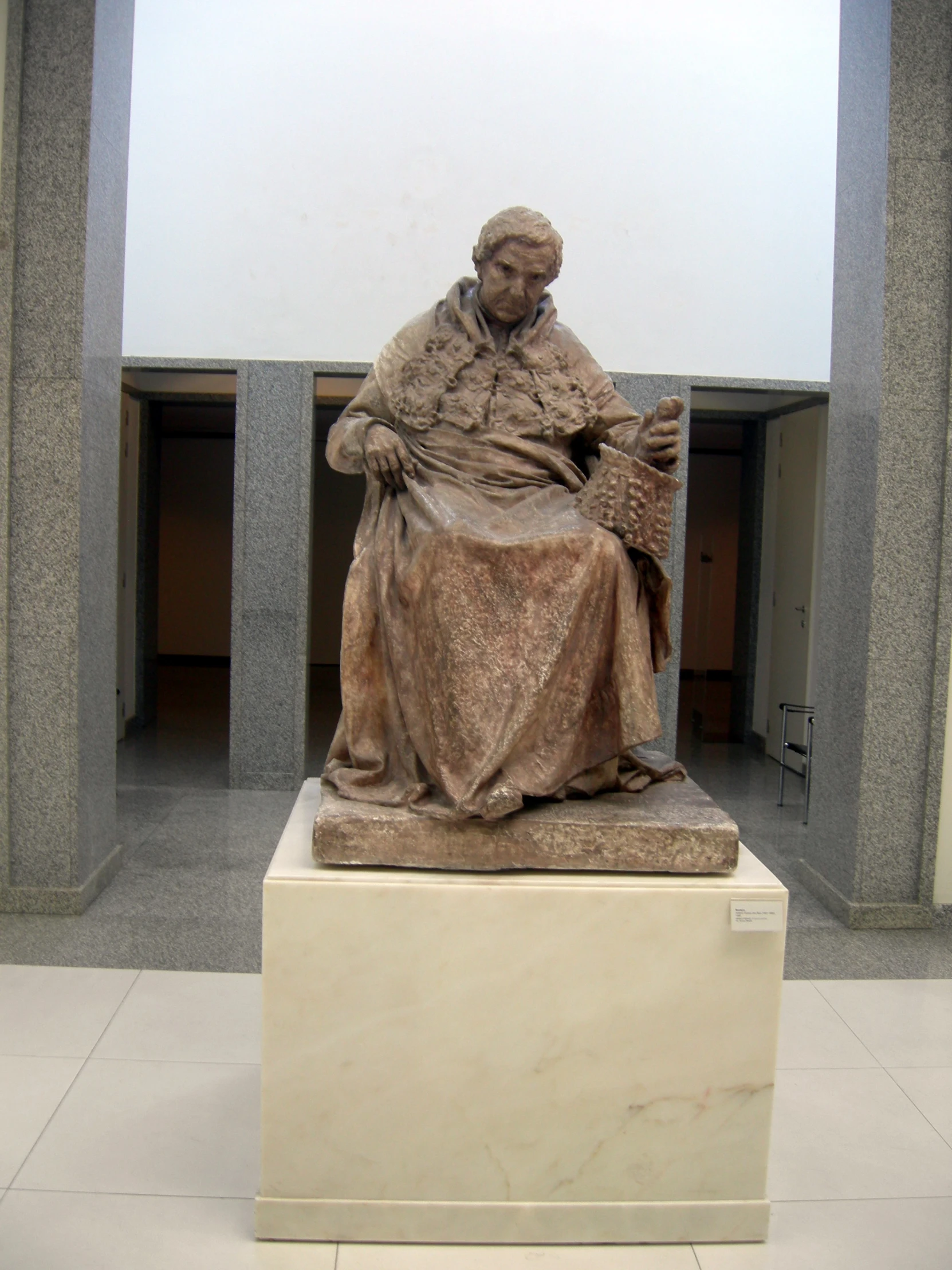 a sculpture of a woman is sitting and reading