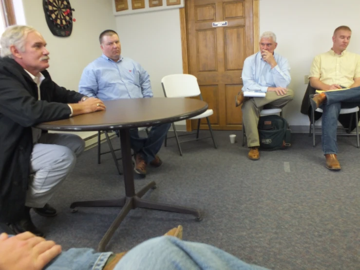 four people are in a circle listening to some speakers