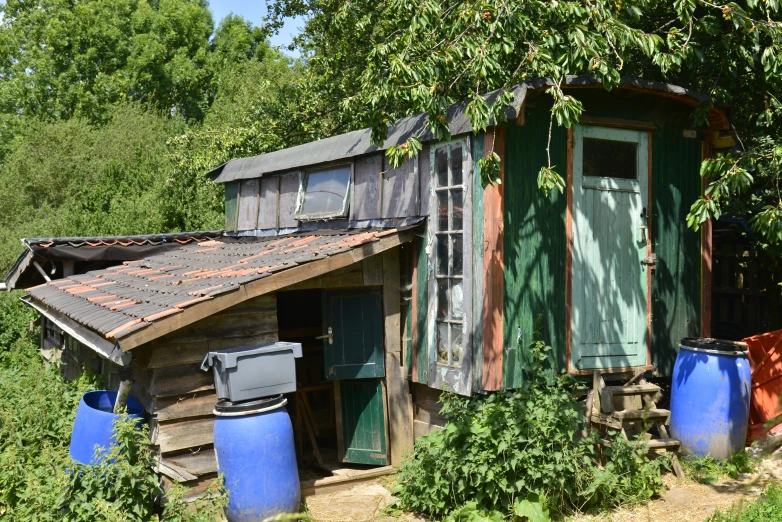 a rustic house that is sitting next to some barrels