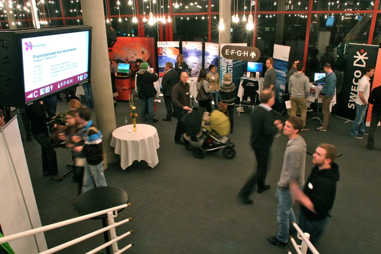 a bunch of people are standing inside and looking at some televisions