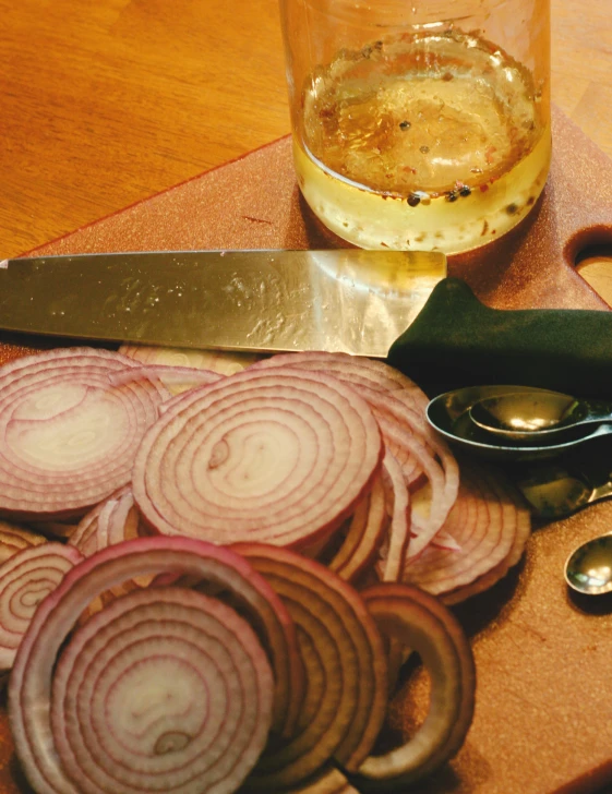 sliced onions on a  board with a glass on the side