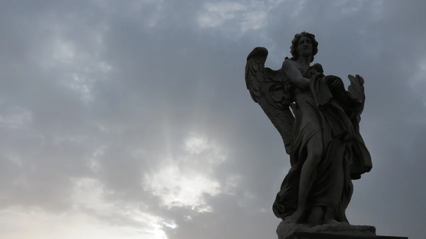 the statue of the angel looks out into the cloudy sky