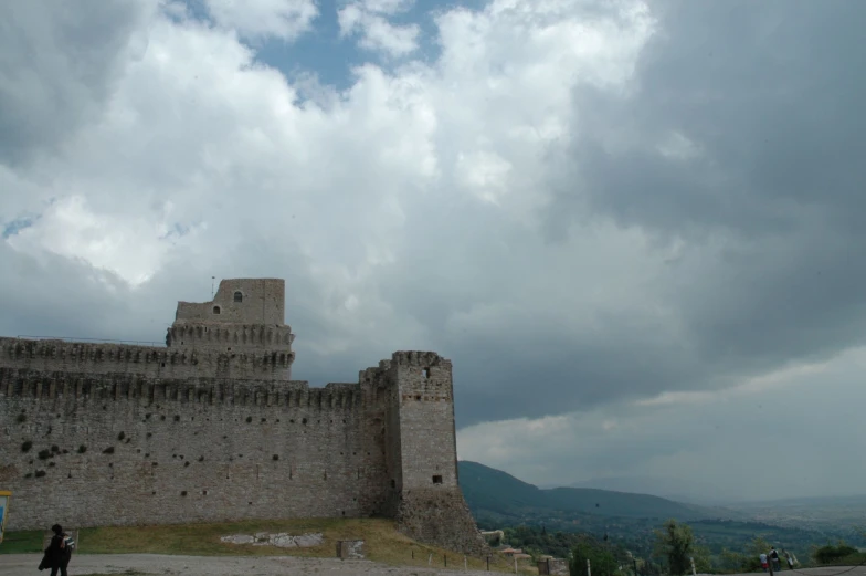 large gray and tan castle wall with a cloudy sky