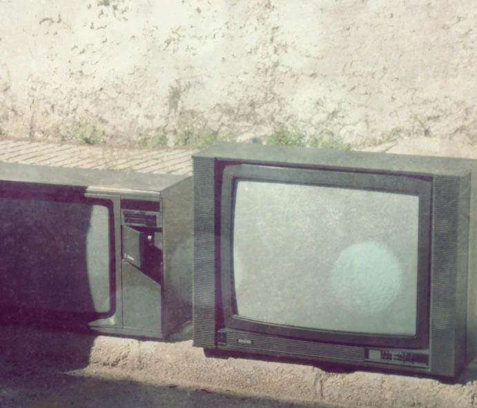 an old tv set sitting next to another television on the ground