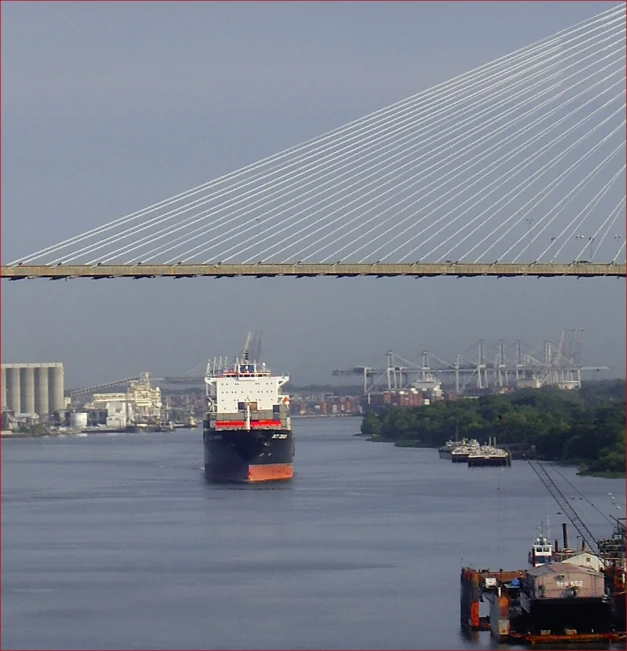 a large boat traveling along a river under a bridge