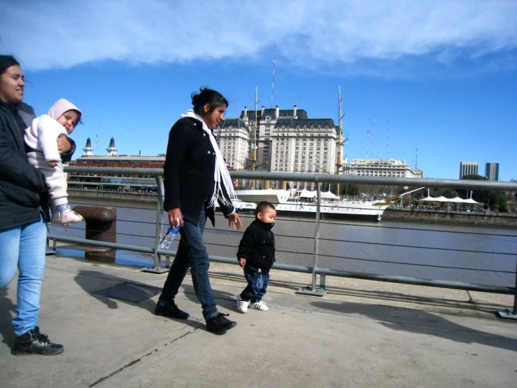 woman and child walk on sidewalk next to water