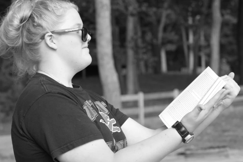 a woman reading a book in front of a tree