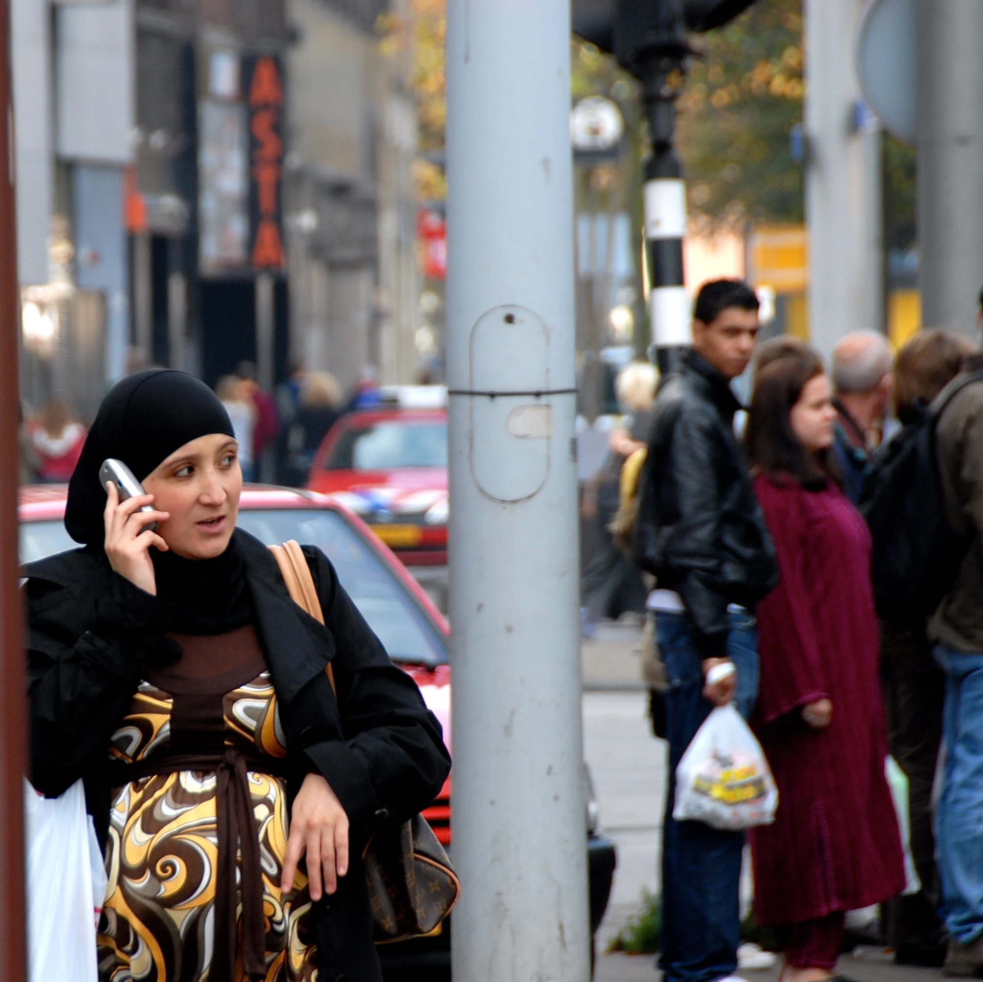 a woman standing on the side of a street talking on a cell phone