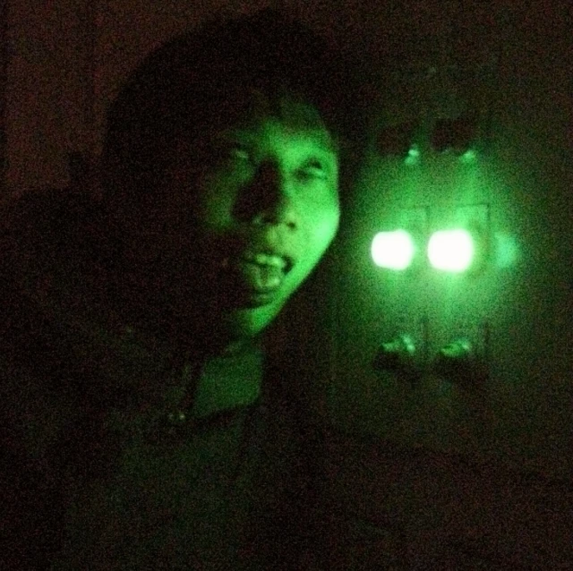 a man holding a glowing flashlight next to a green light