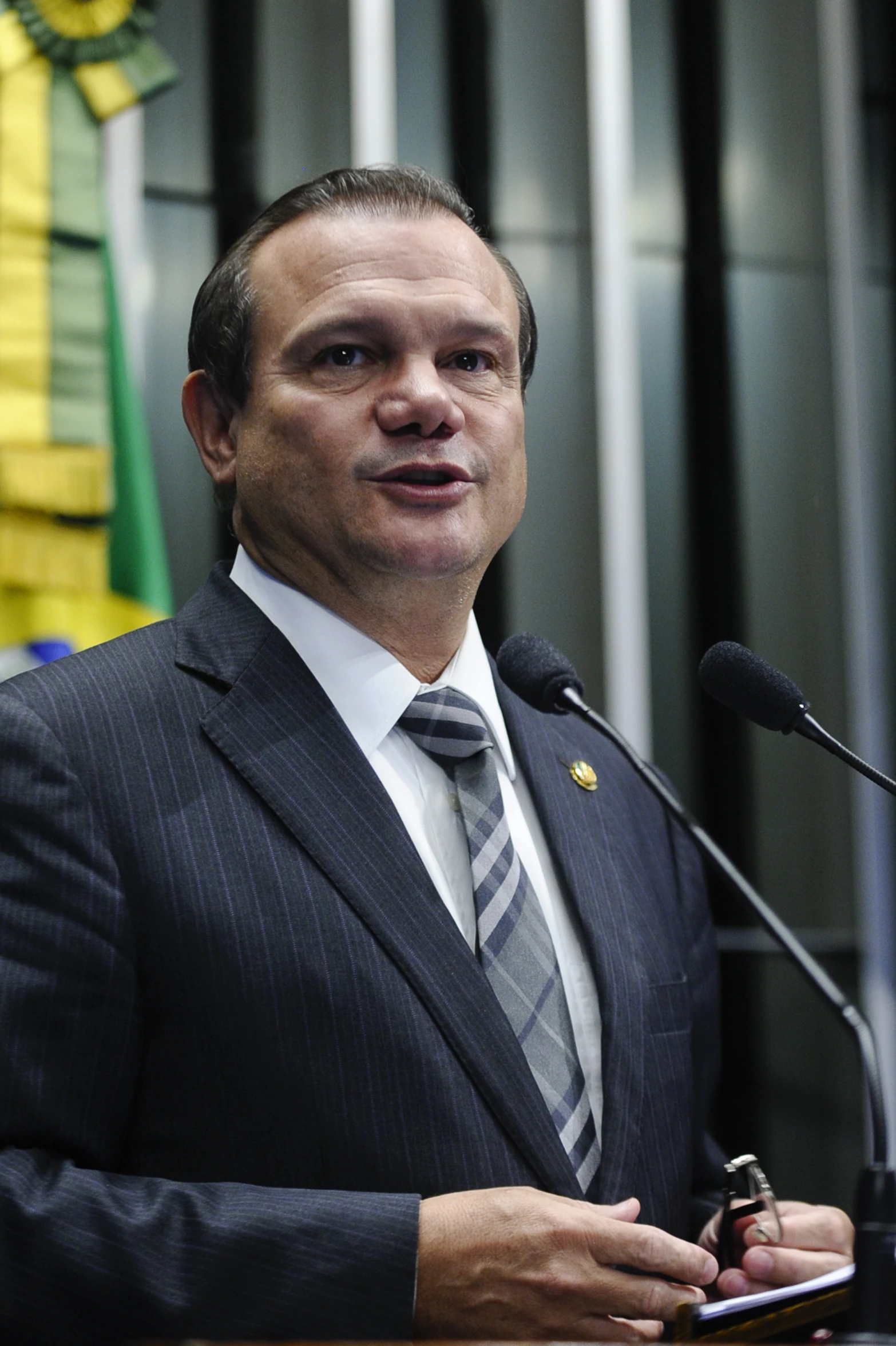 man in suit and tie standing at podium holding a microphone