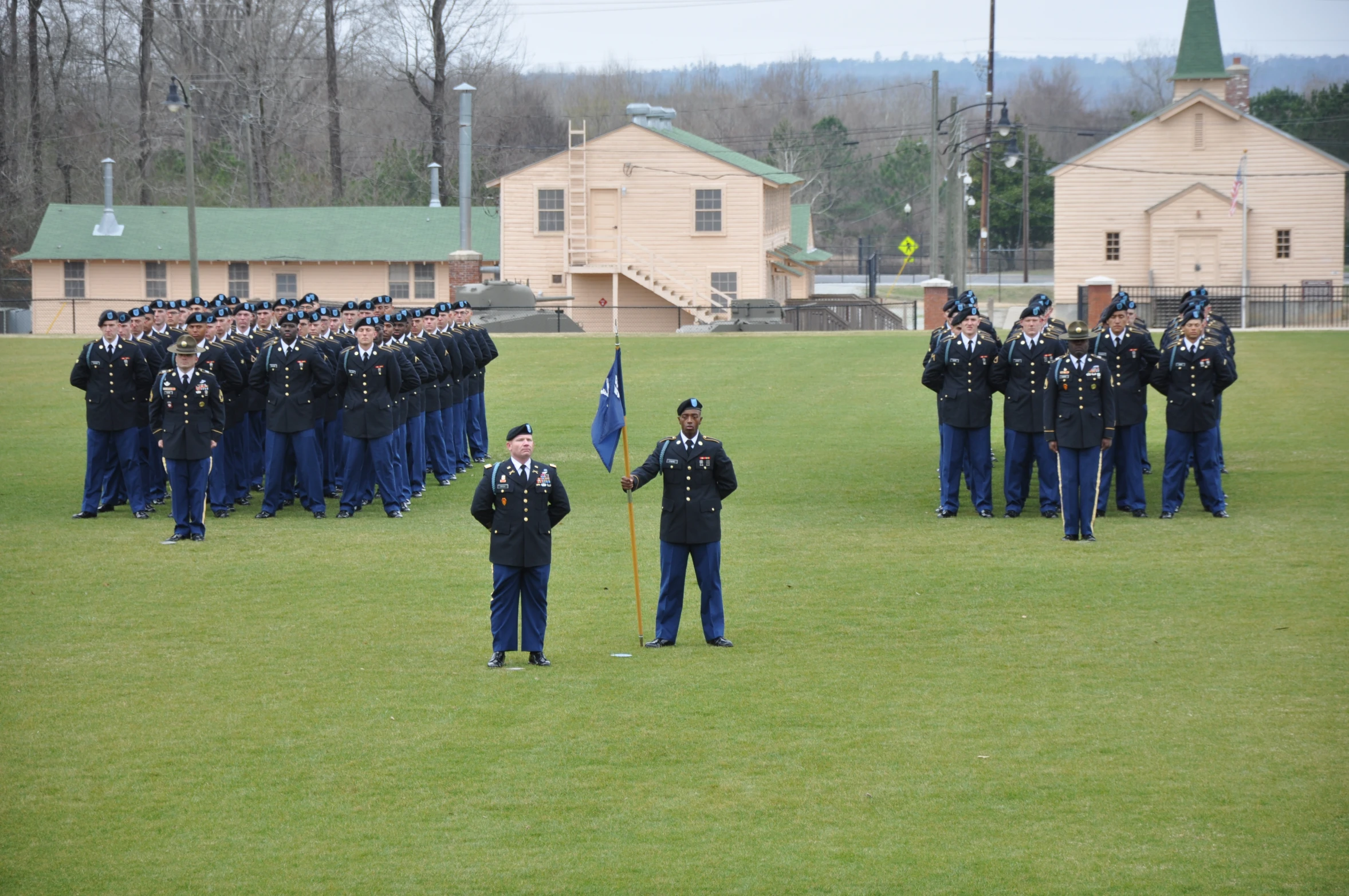 several uniformed men and a flag are lined up in an open field