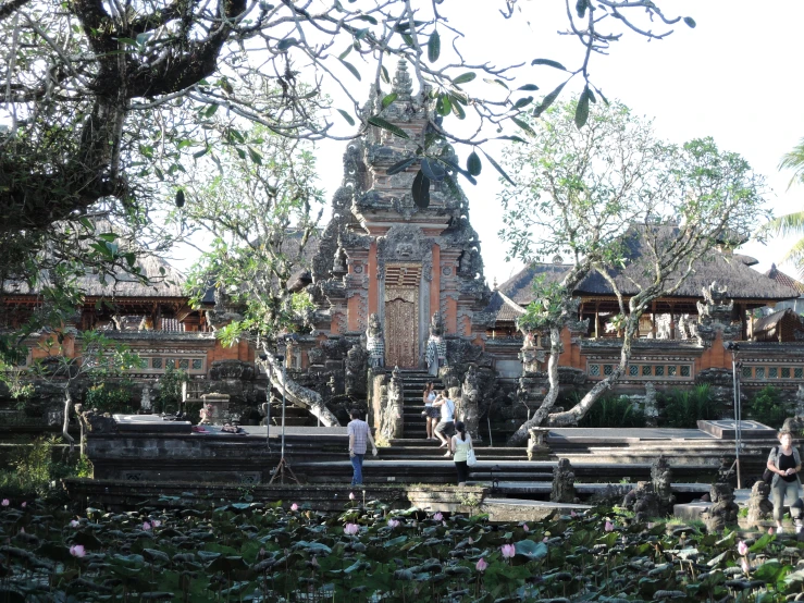 people walking in the water of a river in front of a temple