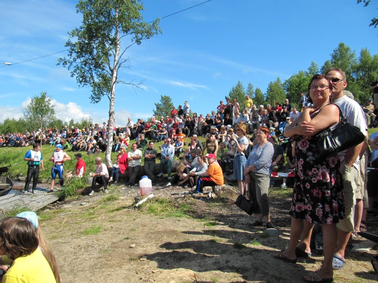 people sitting in the dirt by some water watching soing