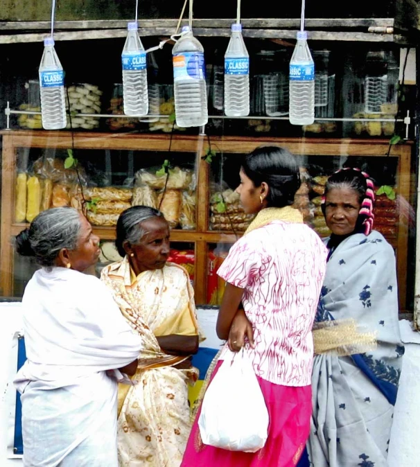 women stand outside of a market and shop,