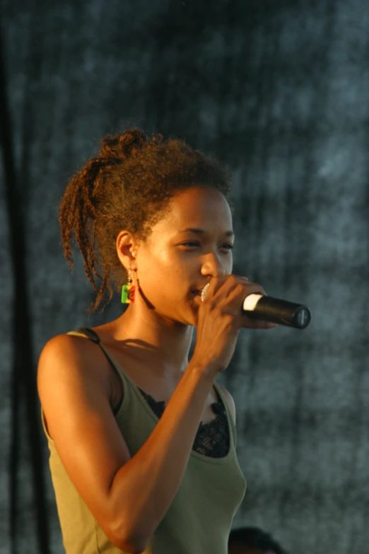 a woman with dread locks standing and singing into a microphone