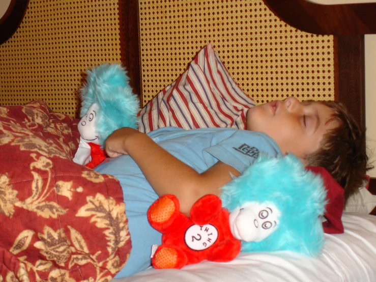 a young child sleeping in bed with some stuffed animals