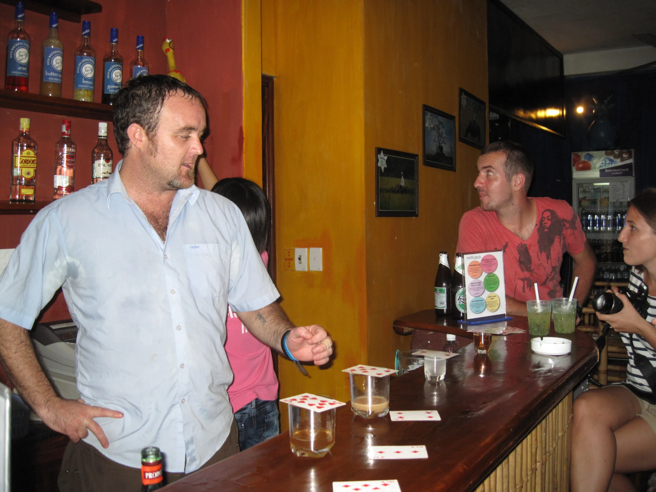 man showing three people how to play cards at a bar