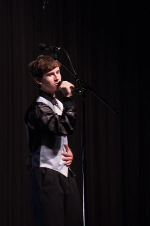 man singing into a microphone on stage with a microphone cord