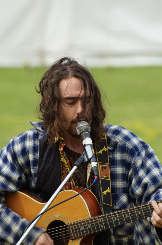 the man is singing into a microphone and playing an acoustic guitar