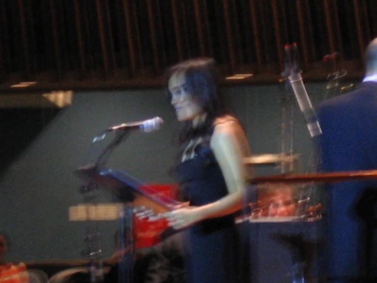 a woman is standing next to a microphone and singing