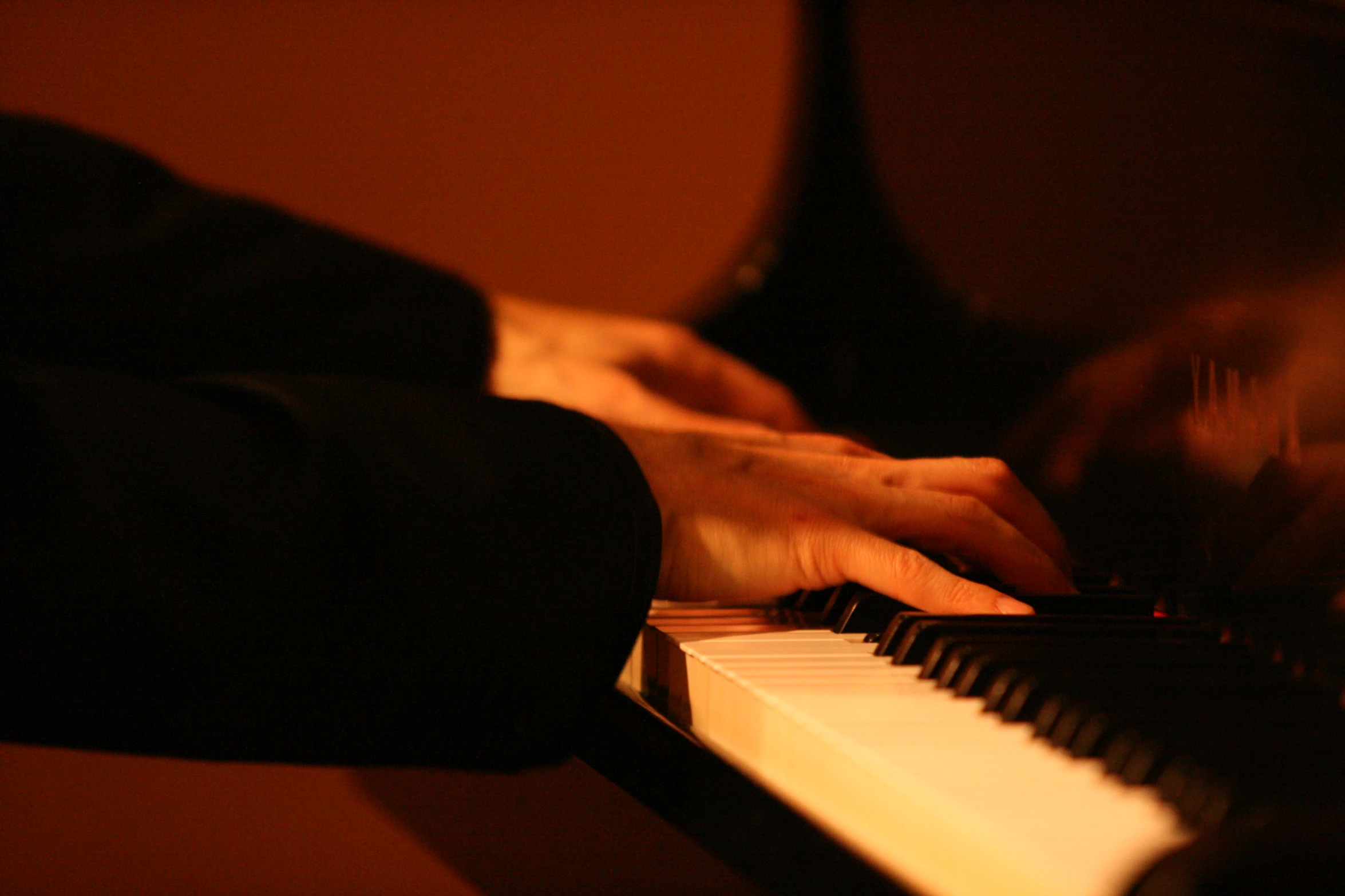 hands holding piano keys with light reflecting on the keyboard