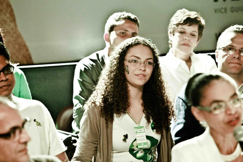 a beautiful young woman sitting next to other people