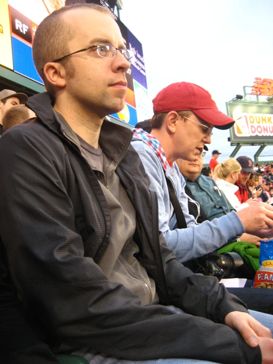 a guy sitting next to another man while holding his phone