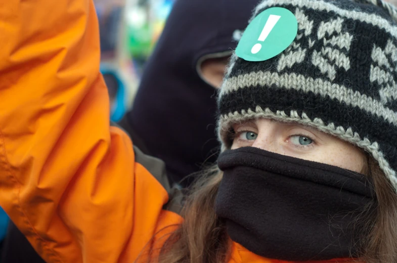 a woman wearing an orange coat and a knitted hat