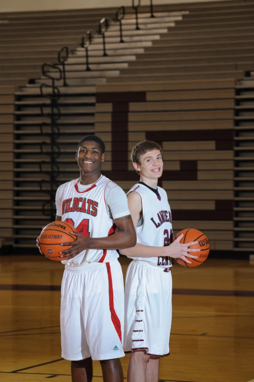 two s stand in a gym while holding basketballs