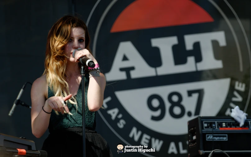 a woman in green dress holding a microphone in front of an atlanta sign