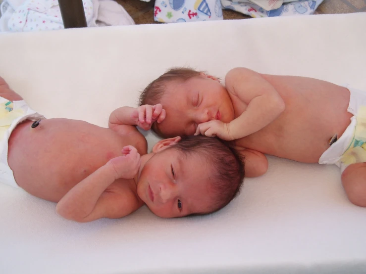 three babies lying on top of a white sheet